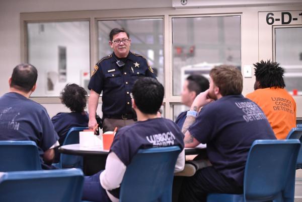 An officer talking in front of a room of incarcerated individuals