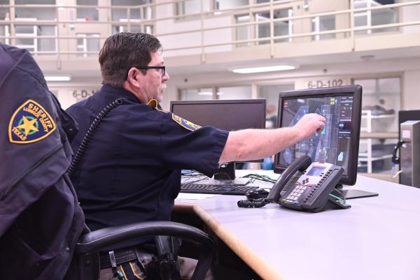 An officer sitting at a desk in a pod, touching a computer screen